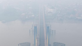 Foto udara sejumlah pengendara melintas di atas jembatan Musi IV Palembang yang tertutup kabut asap di Palembang, Sumatera Selatan, Minggu (4/10/2026). Berdasarkan pantauan aplikasi ISPUnet milik Kementerian Lingkungan Hidup, kualitas udara di Kota P