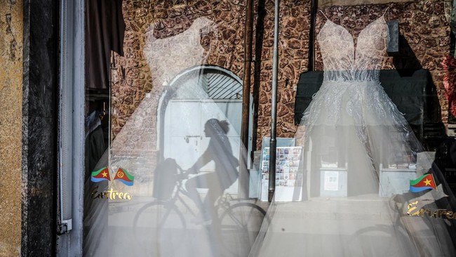 The reflection of a woman riding a bicycle is seen in the window of a wedding gown shop in downtown Asmara, Eritrea, June 18, 2026. Eritrea has long been isolated by the West, which views the East African country as among the most repressive in the w