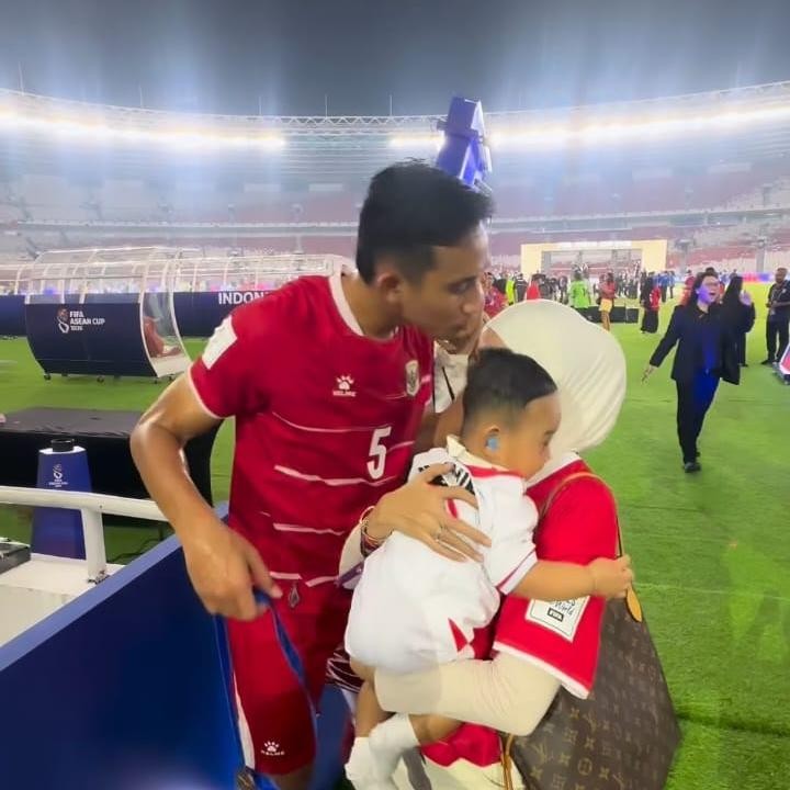 <p>Dalam satu potret yang dibagikan, Rizky Ridho tampak mengecup kening sang istri di lapangan hijau. Usai pertandingan, istri Rizky Ridho turun ke lapangan sambi menggendong sang putra. Keluarga kecil ini merayakan kemenangan bersama. (Foto: Instagram @rizkyridhoramadhani)</p>