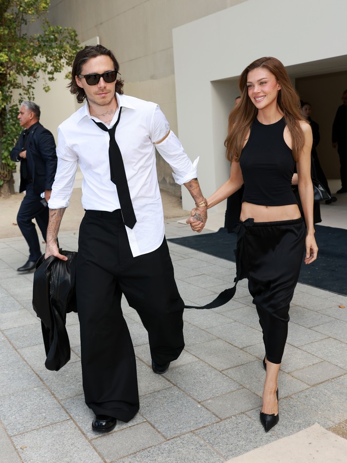 Brooklyn Peltz Beckham&nbsp;dan Nicola Peltz Beckham tampilkan gaya ala couple 90-an dengan outfit hitam dan putih. Brooklyn dengan kemeja dan dasi yang berantakan, sedangkan Nicola mengenakan halter neck tank top dan pencil skirt senada/ Foto: Courtesy of Balenciaga/Getty Images for Balenciaga/Arnold Jerocki