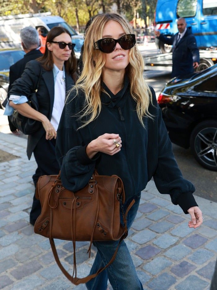 Milly Alcock turut mengenakan outfit kasual, Beauties. Namun kali ini, ia membuat tas Balenciaga City sebagai statement&nbsp;gaya dengan memadukannya bersama jaket dan jeans dalam rona gelap/ Foto: Courtesy of Balenciaga/Getty Images for Balenciaga/Arnold Jerocki