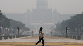 A pedestrian crosses a street as the Prime Ministers Office is shrouded in haze from regional wildfires in Putrajaya, Malaysia, October 7, 2026. REUTERS/Hasnoor Hussain
