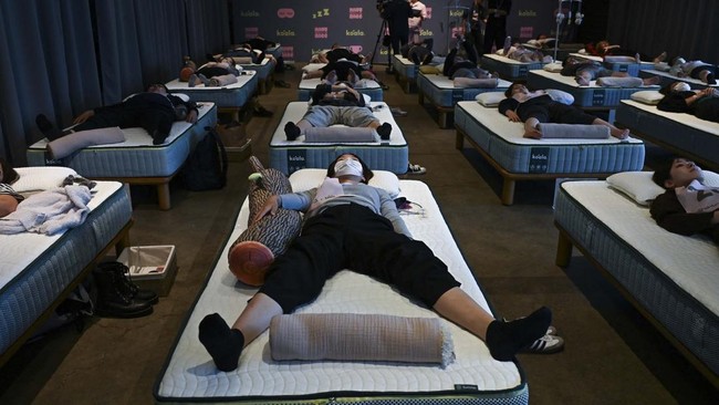 Attendees take part in a sleep competition organized by a mattress brand in Tokyo on October 5, 2026. (Photo by Selim CHTAYTI / AFP)