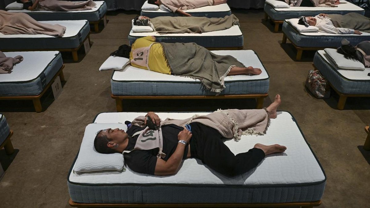 Attendees take part in a sleep competition organized by a mattress brand in Tokyo on October 5, 2026. (Photo by Selim CHTAYTI / AFP)