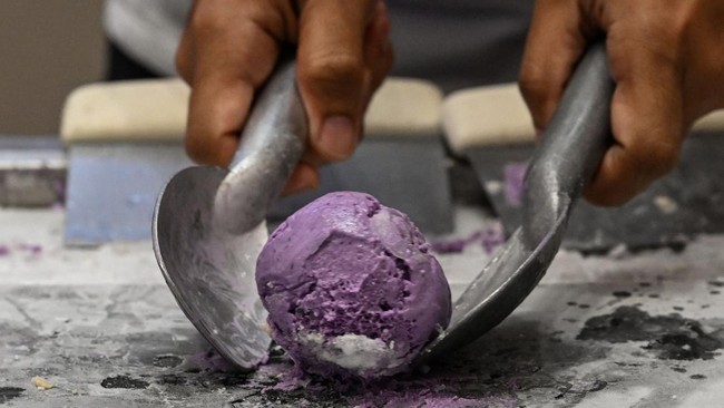 This photo taken on September 23, 2026 shows an employee scooping out ube ice cream during a purple yam promotional event at a mall in Quezon City, Metro Manila. The Philippine ube has become a trend-setting sensation from Los Angeles to London to Se