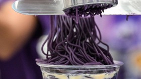 This photo taken on September 23, 2026 shows ube halaya topping over sweet ube rice porridge (champorado) during a purple yam promotional event at a mall in Quezon City, Metro Manila. The Philippine ube has become a trend-setting sensation from Los A