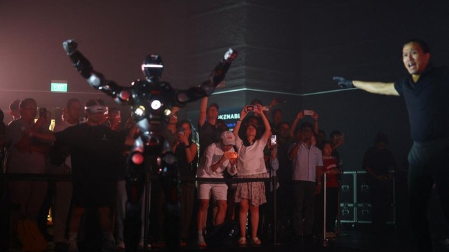 Members of the audience film EngineAI T800 robots fight during ARC League's humanoid combat competition in Singapore October 7, 2026. REUTERS/Edgar Su