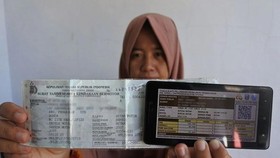 Seorang warga memperlihatkan bukti pelunasan pajak kendaraan bermotor yang dibayar secara daring atau online dari rumah di Panarukan, Situbondo, Jawa Timur. ANTARA FOTO/Seno
