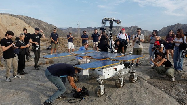 The media stands next to a six-wheeled Mars rover prototype known as Charlie during a test by the European Space Agency (ESA), Airbus and other European partners, testing technologies and operational procedures for ESA's ExoMars Rosalind Franklin mis