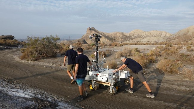 Members of the testing team push a cart with a six-wheeled Mars rover prototype known as Charlie during a test by the European Space Agency (ESA), Airbus and other European partners, testing technologies and operational procedures for ESA's ExoMars R
