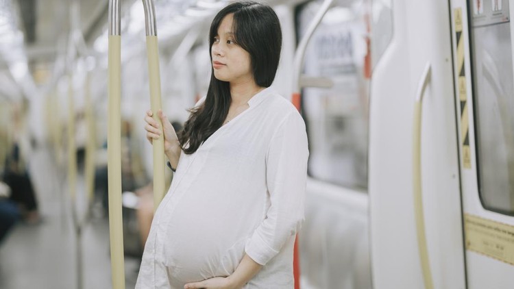 a pregnant asian chinese businesswoman on the move taking public transportation commuter monorail in kuala lumpur to work with her digital tablet