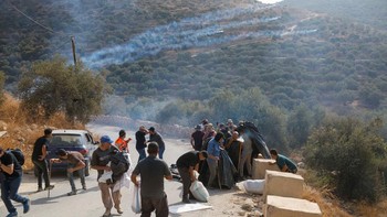 Palestinians, who pick olives during the harvest season, react during clashes with Israeli settlers in Palestinian-owned olive groves in the village of Deir Abu Mishal, with smoke from tear gas seen in the background, near Ramallah, in the Israeli-oc