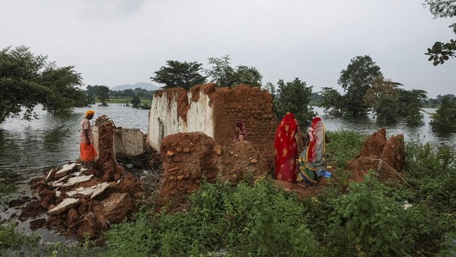 Dhaniram Bhatnagar, a Hindu priest affected by the Ken-Betwa River Linking Project, and his family members search for belongings in the remains of their damaged house, which had been partially submerged in river water, near the Majhgawan Dam on the K