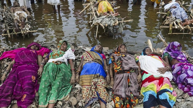 Protesters and members of families affected by the Ken-Betwa River Link Project lie on symbolic funeral pyres placed in the water during a protest near the Majhgawan Dam on the Ken River in ajaygarh, Madhya Pradesh, India, September 20, 2026. REUTERS