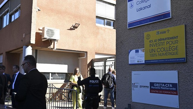 A policeman stands in front of Joseph-Lakanal middle school after a headmaster was injured by a hunting rifle shot and a teenager was arrested in Aubagne, southern France, on October 12, 2026. The school head was hit by a 12-gauge hunting rifle shot,