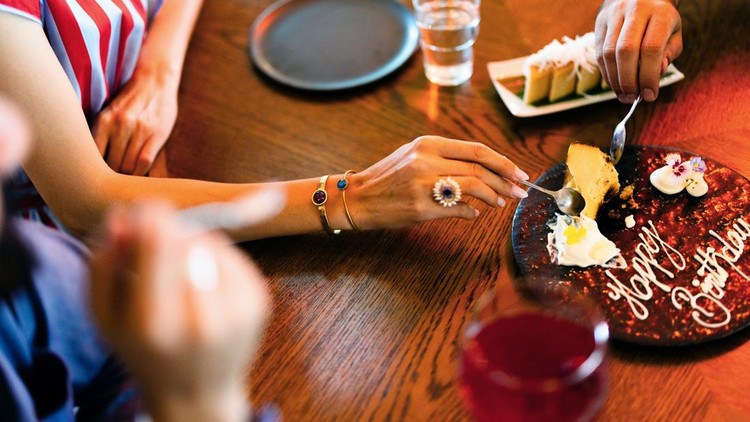 Friends share a birthday dessert on a wooden table&comma; enjoying a casual celebratory moment together&period;