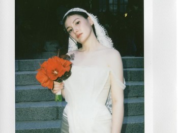 Kim Yong Ji sendiri tampil anggun dalam balutan wedding dress dan wedding veil berwarna putih sambil membawa buket bunga berwarna merah yang cantik./ Foto: instagram.com/demi_kimee
