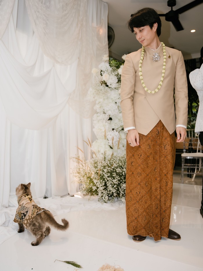 Jimbon, kucing kesayangan Dikta turut menjadi saksi hari bahagia pernikahan. Seperti keluarga dan teman-teman yang hadir, Jimbon pun memakai batik berwarna cokelat senada.&nbsp;(Foto: Instagram.com/dikta/rchelcia)