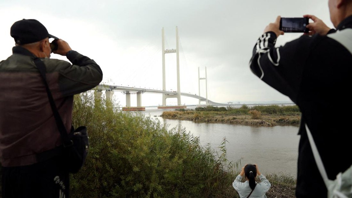 Residents take pictures of the newly opened New Yalu River Bridge, which connects China's Dandong New Zone and North Korea's Sinuiju, in Dandong, Liaoning province, China October 15, 2026. REUTERS/Florence Lo     TPX IMAGES OF THE DAY