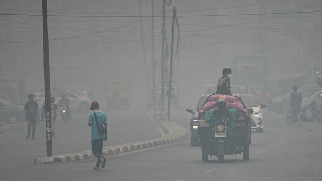 People wearing protective masks ride on a three-wheeled vehicle through a road as haze from wildfires shrouds the area in Palembang, South Sumatra province, Indonesia, October 15, 2026. REUTERS/Abriansyah Liberto