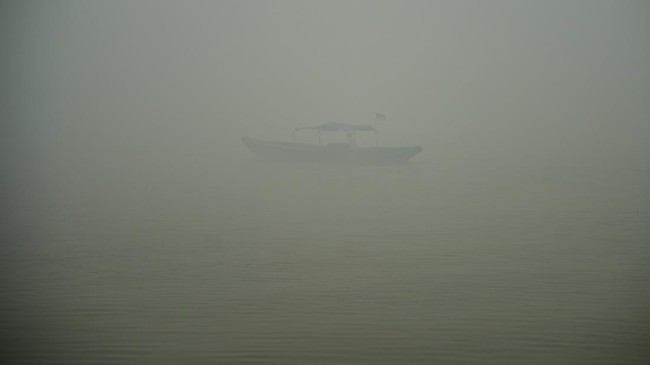 A person rides a wooden boat on the Musi River as haze from wildfires shrouds the area in Palembang, South Sumatra province, Indonesia, October 15, 2026. REUTERS/Abriansyah Liberto