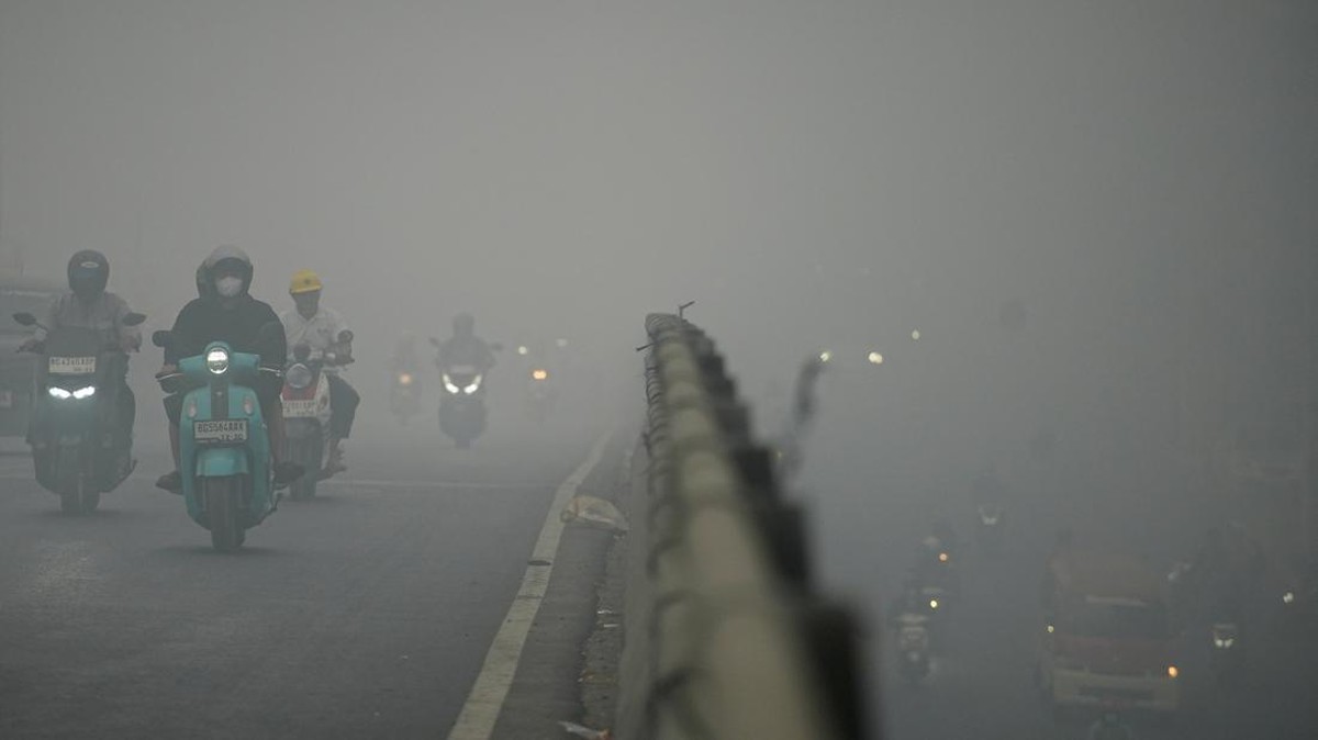 Motorists wearing protective masks ride on a bridge as haze from wildfires shrouds the area in Palembang, South Sumatra province, Indonesia, October 15, 2026. REUTERS/Abriansyah Liberto