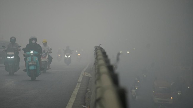 Motorists wearing protective masks ride on a bridge as haze from wildfires shrouds the area in Palembang, South Sumatra province, Indonesia, October 15, 2026. REUTERS/Abriansyah Liberto