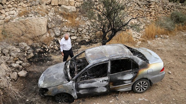 A Palestinian inspects a damaged car, which Palestinians say was burned by Israeli settlers, in Mukhmas, near Ramallah in the Israeli-occupied West Bank, October 14, 2026. REUTERS/Ammar Awad