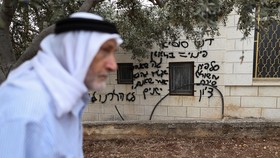 A Palestinian walks past a graffiti sprayed on a wall of a mosque, reading "Regards from Susyia, eviction = mess. Salfit, Meshulash, Shirat Zion. The fact we are quiet does not mean we are sleeping, we didnt go anywhere", which Palestinians say was s