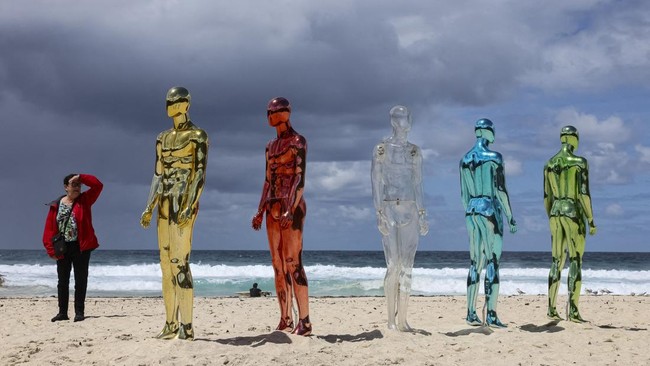 A woman stands next to a sculpture titled ART (Artificial Real Time) by artist Erica Zaino on the opening day of the 'Sculpture by the Sea' outdoor exhibition in Bondi, Sydney, Australia, October 16, 2026. REUTERS/Hollie Adams     TPX IMAGES OF THE D
