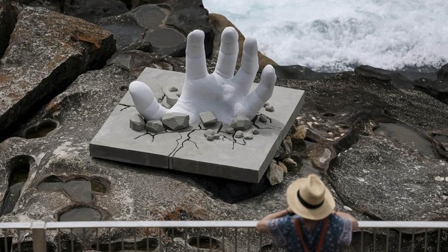 A woman looks at a sculpture titled Surface Breach by artist Andre Braun on the opening day of the 'Sculpture by the Sea' outdoor exhibition in Bondi, Sydney, Australia, October 16, 2026. REUTERS/Hollie Adams     TPX IMAGES OF THE DAY