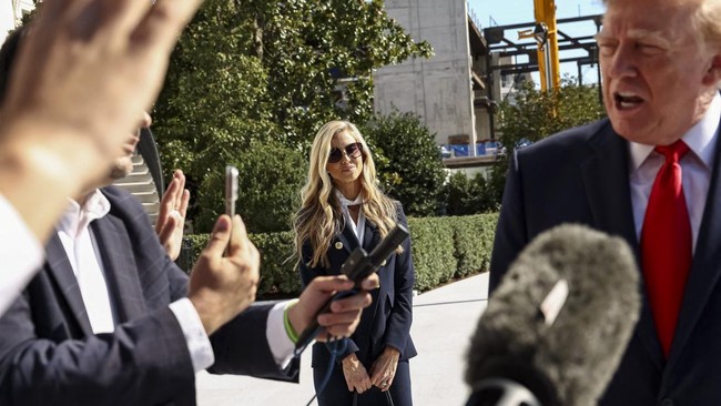 New White House Press Secretary Katie Zacharia listens to US President Donald Trump speaking to the media as he departs the White House in Washington, DC, US, October 13, 2026.    REUTERS/Kevin Lamarque