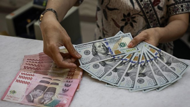 Karyawan menunjukkan uang pecahan rupiah dan dolar Amerika Serikat (AS) di gerai penukaran mata uang asing Ayu Masagung, Jakarta, Jumat (16/10/2026). Nilai tukar rupiah terhadap dolar AS pada pembukaan perdagangan Jumat pagi melemah 83 poin atau 0,46