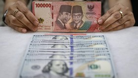 Karyawan menunjukkan uang pecahan rupiah dan dolar Amerika Serikat (AS) di gerai penukaran mata uang asing Ayu Masagung, Jakarta, Jumat (16/10/2026). Nilai tukar rupiah terhadap dolar AS pada pembukaan perdagangan Jumat pagi melemah 83 poin atau 0,46