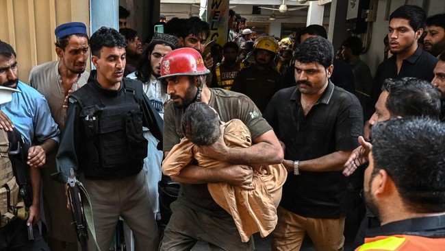 A rescuer carries a child during a search operation after a roof collapsed at a school in Peshawar on October 15, 2026. Twenty-seven pupils and a teacher were killed on October 15 after a roof collapsed at a school in the northwest Pakistani city of 