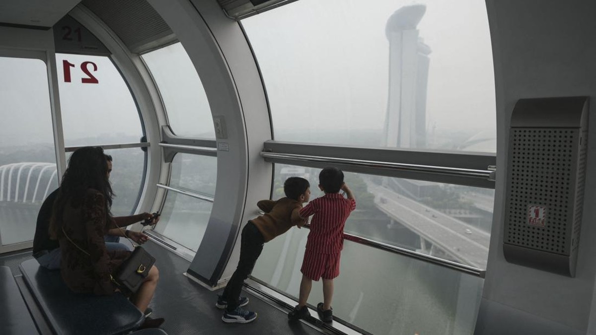 A family looks out of a cabin in the Singapore Flyer in Singapore on October 15, 2026, as the country continues to be shrouded in haze caused by fires in Indonesia. Toxic haze has covered parts of Indonesia, Malaysia and Singapore for weeks as Jakart