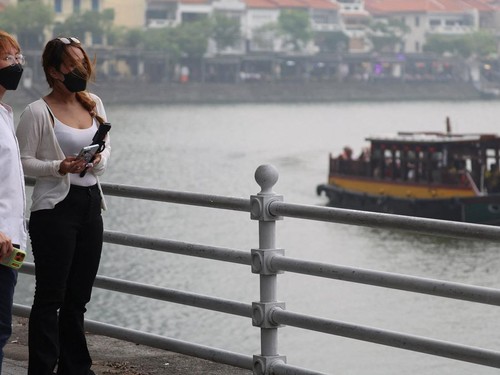 People wear face-mask as a tourist-oriented bumboat moves through the Singapore River, with restaurants at Boat Quay in the background, in haze-shrouded Singapore, October 16, 2026. REUTERS/Edgar Su