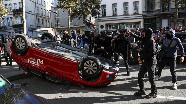 Demonstrators step onto an overturned car during a students' protest in Brussels, Belgium, October 17, 2026. REUTERS/Yves Herman