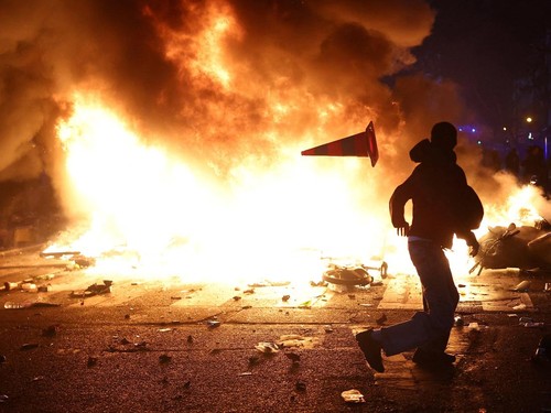 A protesters sit on chairs from a vandalized shop as they block a street amid clashes during a day of demonstrations against the cost of living and rising fuel prices in Paris as part of nationwide protests called by the "Yellow Vests" movement, join