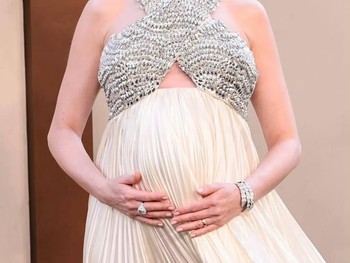 Definisi pregnancy glow, ia tampil dengan gaun berwarna ivory dengan detail halter neck potongan silang yang dihiasi embellishment silver sehingga membuatnya terlihat semakin glam/ Foto: Instagram.com/annehathaway.daily