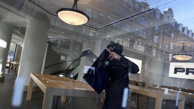 A protester steals an Apple screen at the Apple Store which has been ransacked during ongoing protest action against the