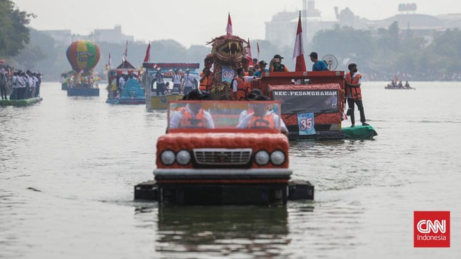 Warga menyaksikan parade perahu berbahan limbah botol plastik dan galon dalam Festival Cinta Lingkungan (Cilung) di Danau Sunter, Jakarta, Minggu (18/10). (CNN Indonesia/Febria Adha L)