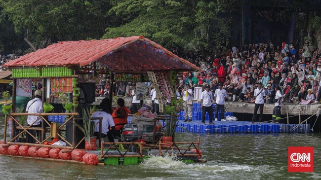 Warga menyaksikan parade perahu berbahan limbah botol plastik dan galon dalam Festival Cinta Lingkungan (Cilung) di Danau Sunter, Jakarta, Minggu (18/10). (CNN Indonesia/Febria Adha L)