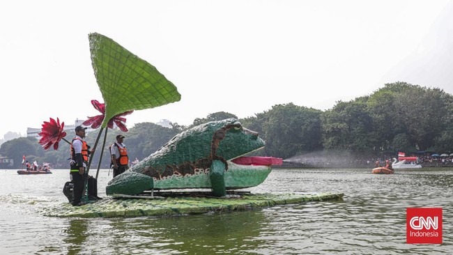 Warga menyaksikan parade perahu berbahan limbah botol plastik dan galon dalam Festival Cinta Lingkungan (Cilung) di Danau Sunter, Jakarta, Minggu (18/10). (CNN Indonesia/Febria Adha L)
