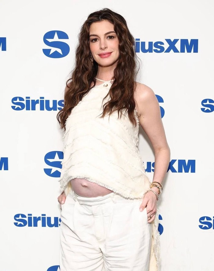 Tampil kasual dengan halter neck berwarna ivory yang dipadukan celana putih saat mengunjungi SiriusXM Studios untuk promosi film The Odyssey/ Foto: Instagram.com/archivehathaway