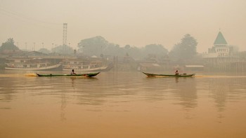 People ride wooden boats on the Kahayan River as haze from wildfires shrouds Palangka Raya, Central Kalimantan province, Indonesia, October 18, 2026. REUTERS/Arief Rahman Septian Prathama