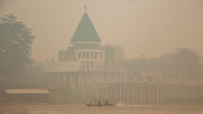 People ride a wooden boat on the Kahayan River as haze from wildfires shrouds Palangka Raya in Central Kalimantan province, Indonesia, October 18, 2026. REUTERS/Arief Rahman Septian Prathama