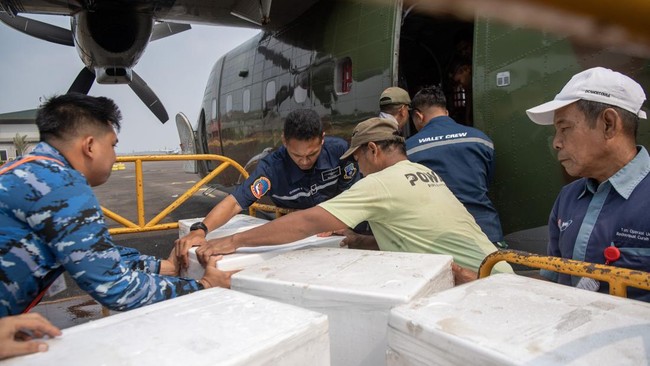 Prajurit TNI AU dibantu pekerja memindahkan boks berisi dry ice atau es kering sebagai bahan semai untuk Operasi Modifikasi Cuaca (OMC) ke dalam pesawat Cassa C-212 milik Skadron IV Wing Udara 1.2 Grup 1 Angkut Lanud Abdulrachman Saleh di Base Ops La
