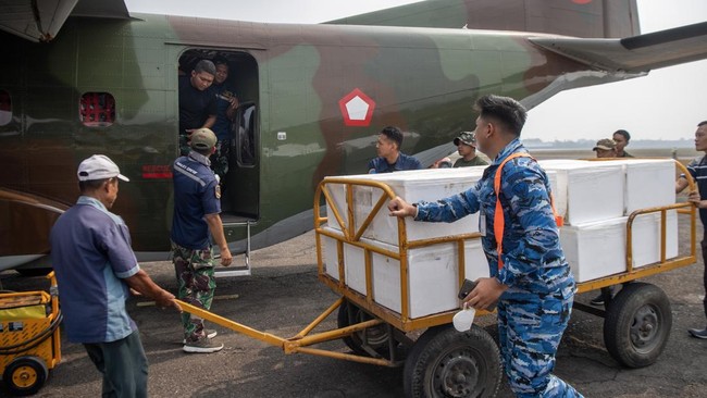 Prajurit TNI AU dibantu pekerja memindahkan boks berisi dry ice atau es kering sebagai bahan semai untuk Operasi Modifikasi Cuaca (OMC) ke dalam pesawat Cassa C-212 milik Skadron IV Wing Udara 1.2 Grup 1 Angkut Lanud Abdulrachman Saleh di Base Ops La