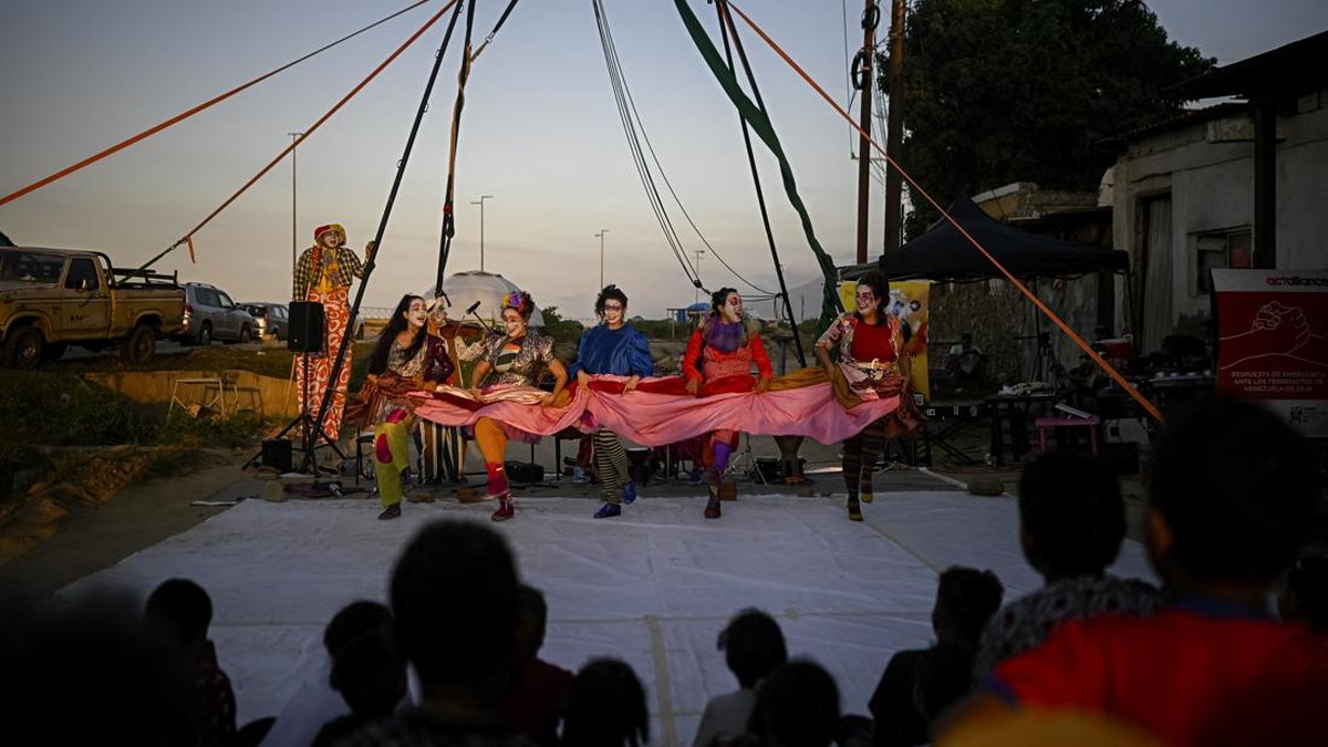 People watch a performance by members of the TET Center for Artistic Creation during the 6th Social Festival of Performing Arts in Playa Verde, Catia La Mar, La Guaira state, Venezuela, on October 18, 2026. The TET Center for Artistic Creation perfor